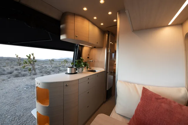 Noovo Next galley and dinette bench at dusk with the sliding door open to the desert