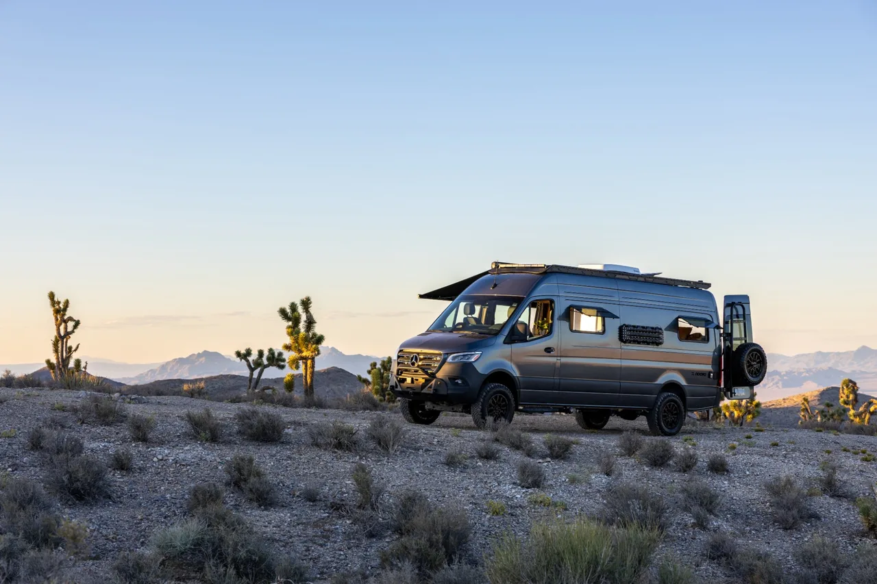 Noovo Next camper van on a Mercedes-Benz Sprinter AWD chassis parked in the desert at golden hour with the awning extended