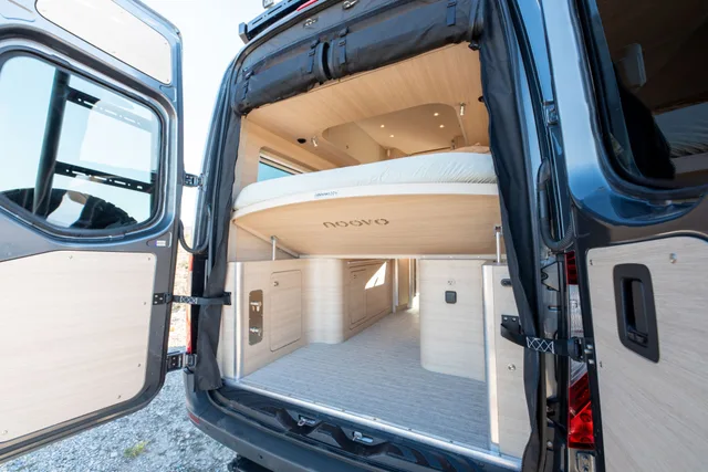 Noovo Next rear doors open showing the power lift queen bed raised over the gear garage